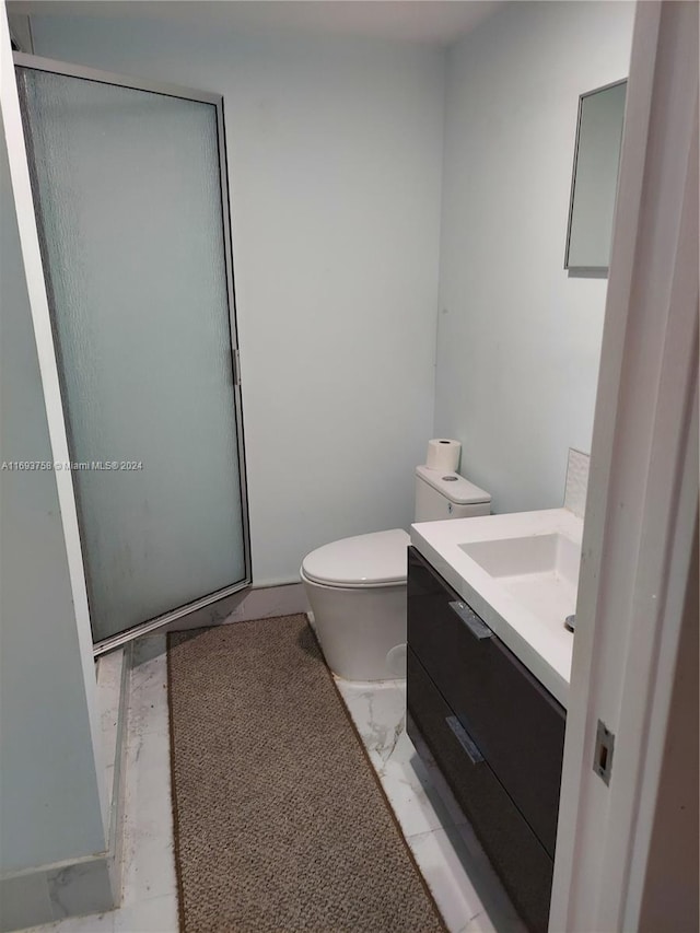 bathroom featuring vanity, an enclosed shower, and toilet