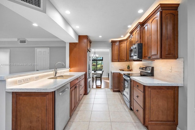 kitchen featuring sink, light tile patterned floors, appliances with stainless steel finishes, kitchen peninsula, and a chandelier