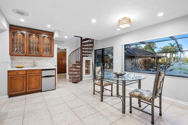 kitchen with light tile patterned floors, backsplash, fridge, and sink