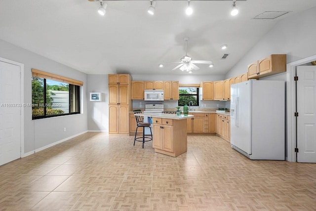 kitchen featuring a kitchen island, a breakfast bar, ceiling fan, a healthy amount of sunlight, and white appliances