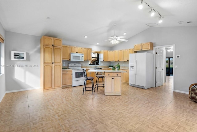 kitchen featuring lofted ceiling, white appliances, a breakfast bar area, ceiling fan, and a kitchen island