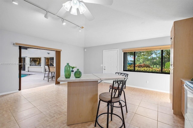 kitchen featuring lofted ceiling, a breakfast bar area, track lighting, kitchen peninsula, and ceiling fan