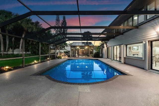 pool at dusk featuring a patio and glass enclosure