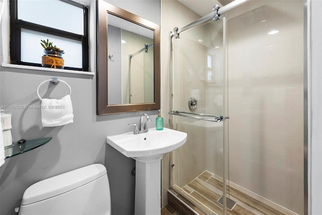 bathroom with toilet, an enclosed shower, and hardwood / wood-style flooring