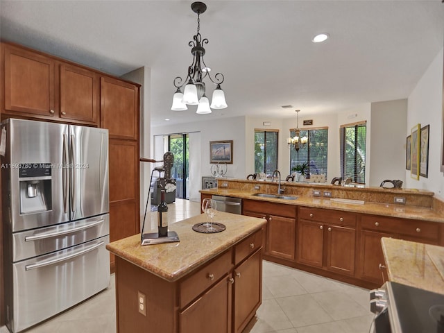 kitchen with stainless steel appliances, sink, decorative light fixtures, an inviting chandelier, and a kitchen island