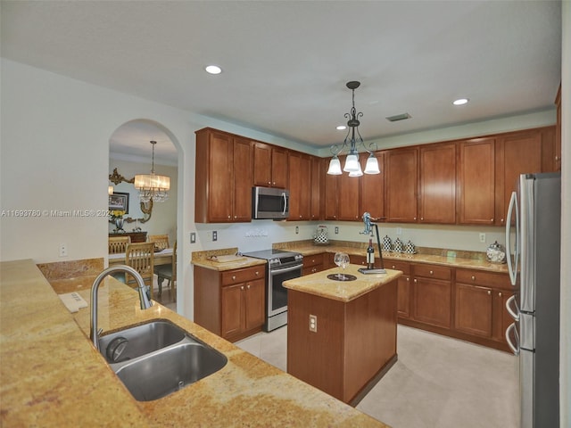 kitchen with sink, an inviting chandelier, pendant lighting, a kitchen island with sink, and appliances with stainless steel finishes