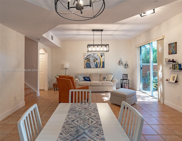 dining space featuring an inviting chandelier, light tile patterned floors, and a textured ceiling