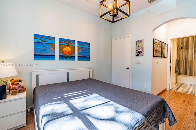 bedroom featuring ensuite bathroom, a notable chandelier, and hardwood / wood-style flooring