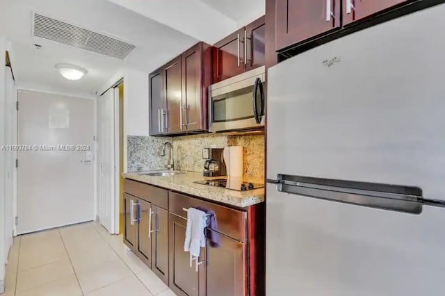 kitchen with light stone countertops, sink, stainless steel appliances, backsplash, and light tile patterned floors