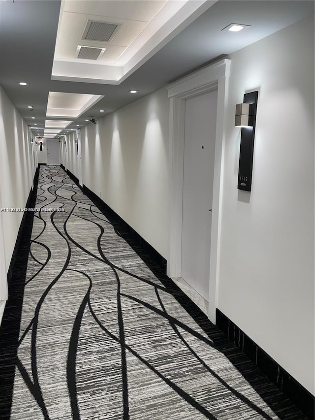 corridor featuring a tray ceiling and carpet flooring