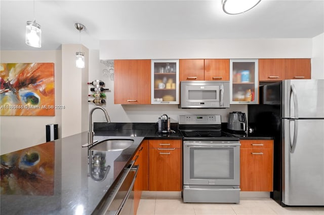 kitchen with pendant lighting, dark stone counters, sink, light tile patterned floors, and stainless steel appliances