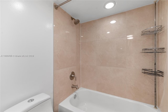 bathroom with tiled shower / bath combo and toilet