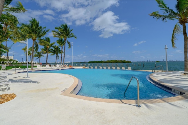 view of swimming pool with a patio area and a water view