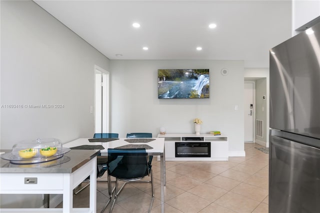 kitchen with stainless steel refrigerator, black oven, and light tile patterned flooring