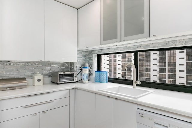 kitchen with backsplash, dishwasher, white cabinets, and sink