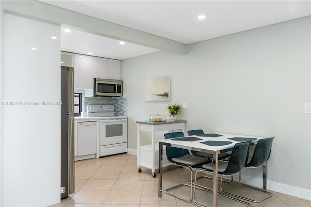 kitchen featuring decorative backsplash, white cabinetry, light tile patterned flooring, and appliances with stainless steel finishes