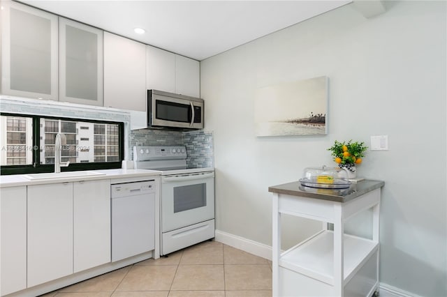 kitchen with white cabinetry, sink, white appliances, decorative backsplash, and light tile patterned floors