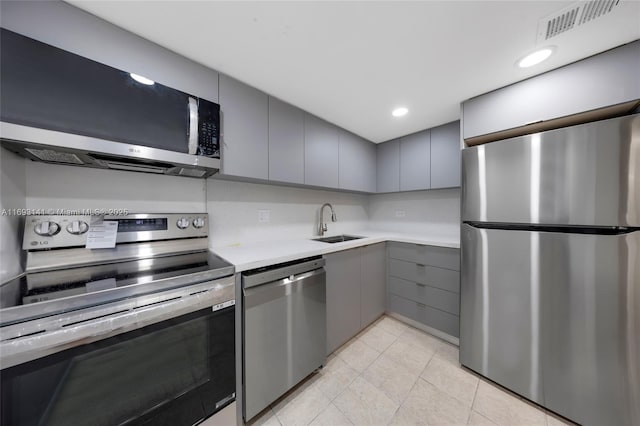 kitchen featuring appliances with stainless steel finishes, sink, light tile patterned floors, and gray cabinetry