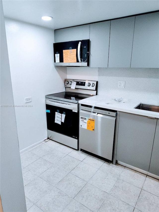 kitchen featuring sink, light tile patterned floors, and appliances with stainless steel finishes