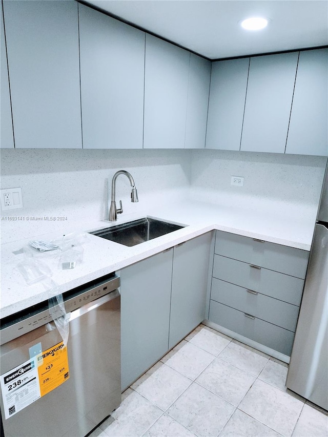 kitchen with light stone countertops, gray cabinetry, stainless steel appliances, sink, and light tile patterned floors