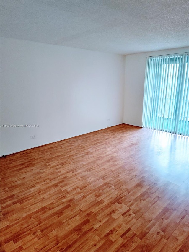 spare room featuring a textured ceiling and light hardwood / wood-style flooring