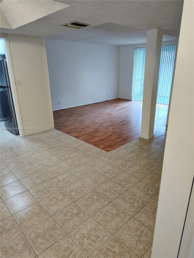 spare room featuring a textured ceiling and light hardwood / wood-style flooring