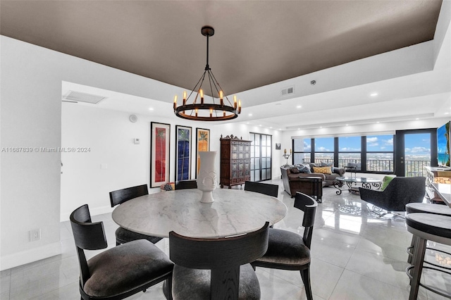 dining area featuring a notable chandelier, light tile patterned flooring, french doors, and a tray ceiling