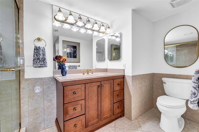 bathroom with tile patterned floors, vanity, tile walls, and toilet