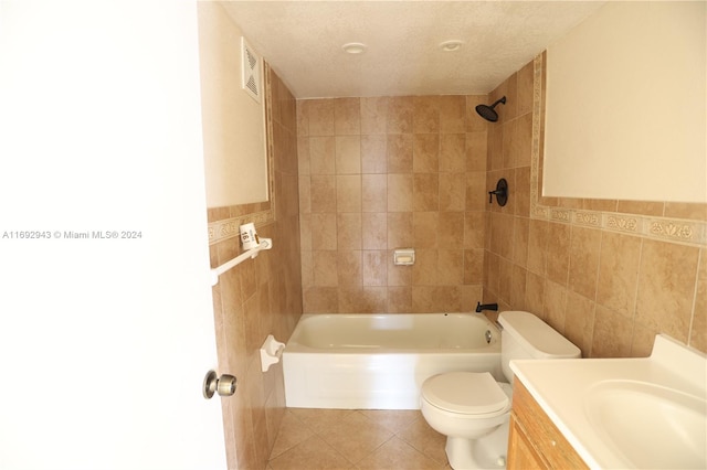 full bathroom with tile patterned flooring, tiled shower / bath combo, toilet, a textured ceiling, and tile walls