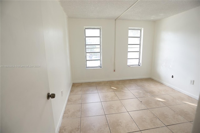 tiled empty room with a textured ceiling