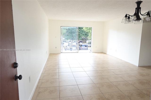 tiled empty room with a notable chandelier and a textured ceiling