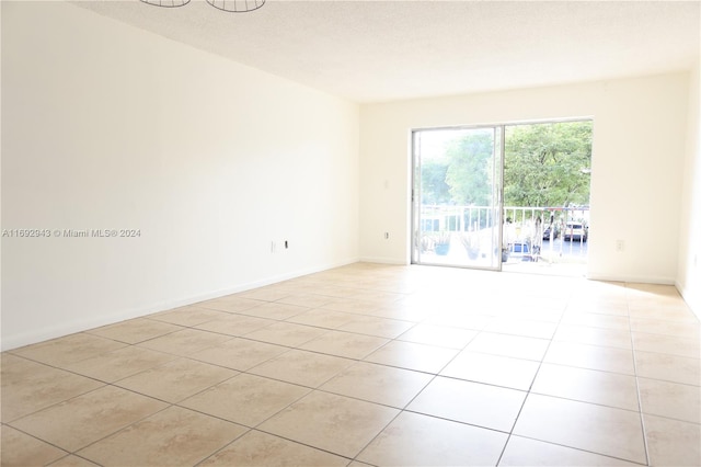 tiled empty room featuring a textured ceiling