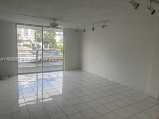 spare room with tile patterned flooring, track lighting, and a ceiling fan