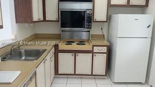 kitchen with white fridge, light tile patterned floors, and sink