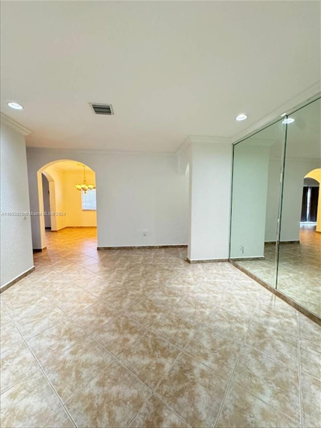 tiled spare room featuring a notable chandelier