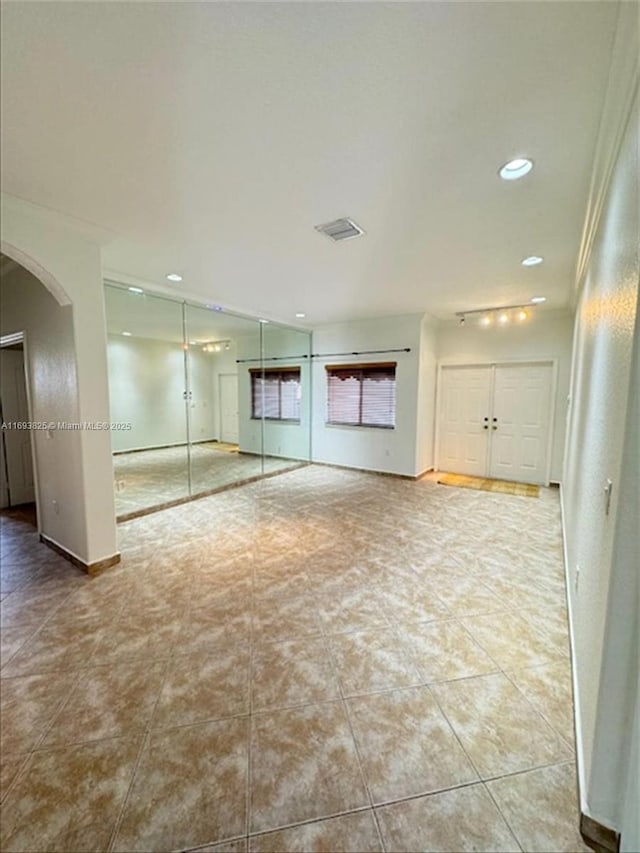 interior space with arched walkways, light tile patterned floors, recessed lighting, visible vents, and baseboards