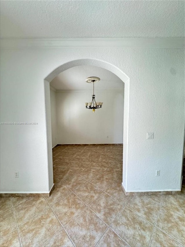 tiled empty room featuring a textured ceiling and crown molding