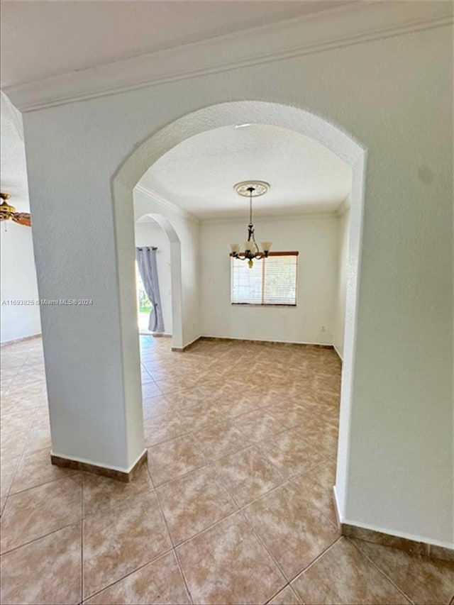 corridor with tile patterned flooring, crown molding, and a chandelier