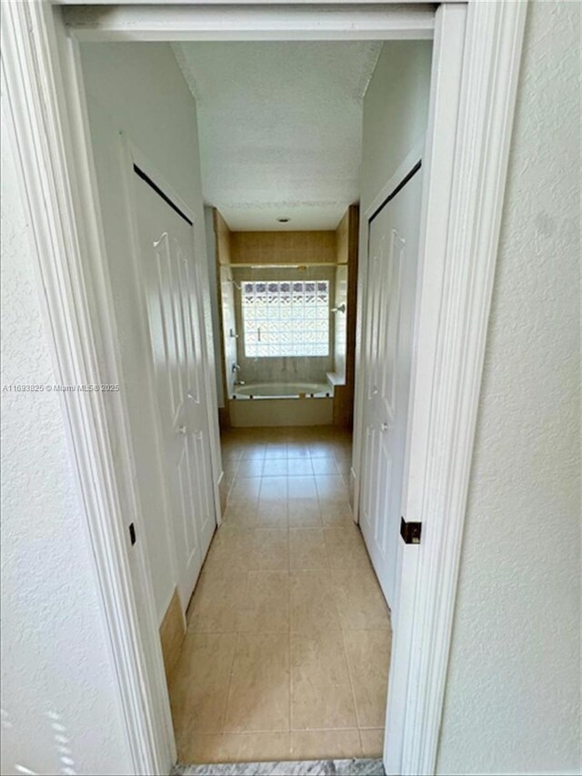 hallway with light tile patterned floors and a textured ceiling