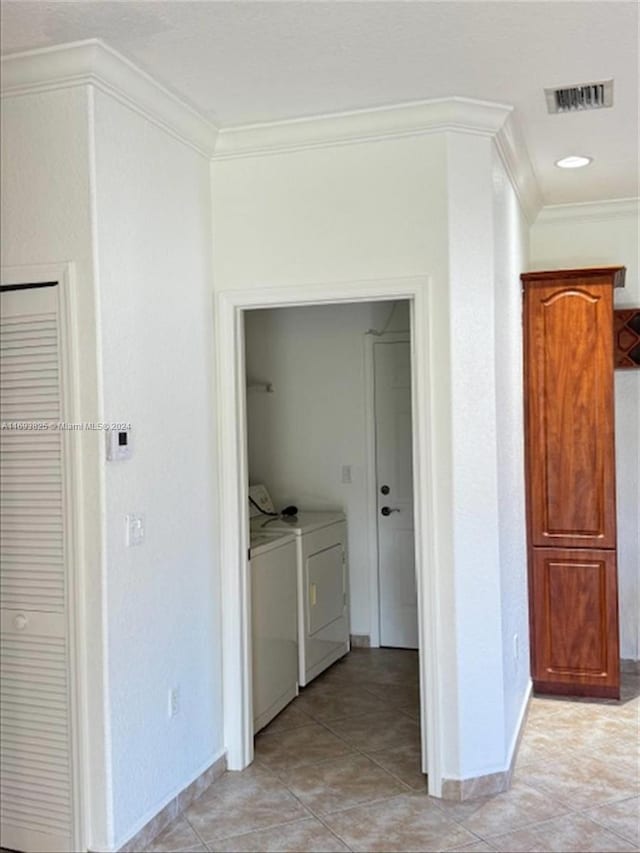 hall featuring light tile patterned floors, washer and dryer, and ornamental molding