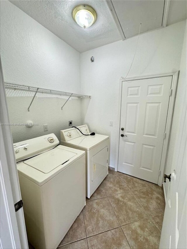 laundry area featuring independent washer and dryer, a textured ceiling, and light tile patterned floors