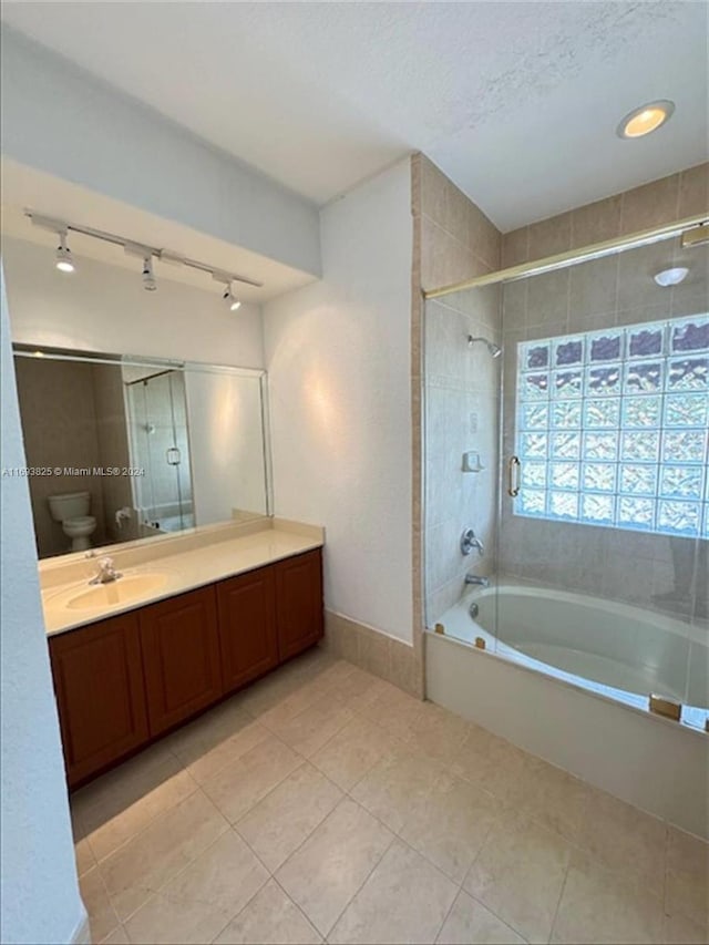 full bathroom featuring tiled shower / bath combo, tile patterned floors, a textured ceiling, toilet, and vanity