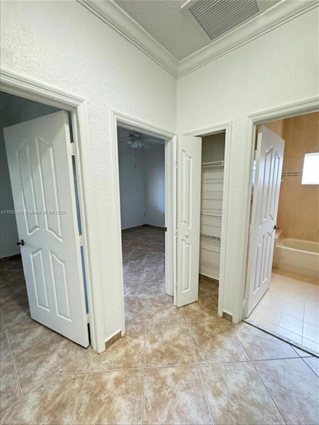 unfurnished bedroom with light tile patterned floors, crown molding, and connected bathroom