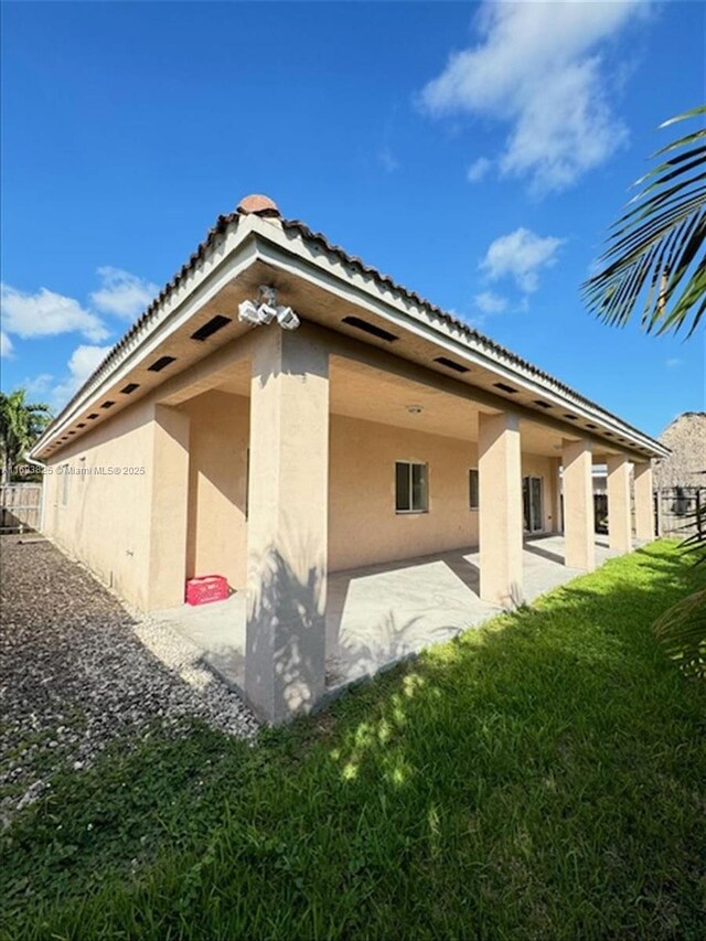 back of house with a patio and a lawn