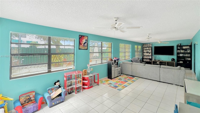 recreation room with ceiling fan, light tile patterned floors, and a textured ceiling