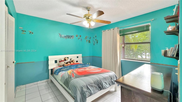 tiled bedroom with ceiling fan and a textured ceiling