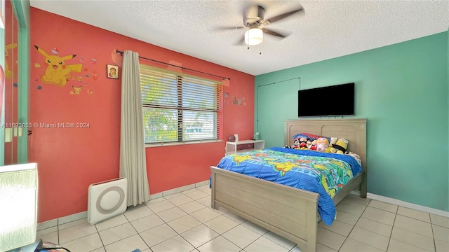 bedroom with ceiling fan, light tile patterned flooring, and a textured ceiling