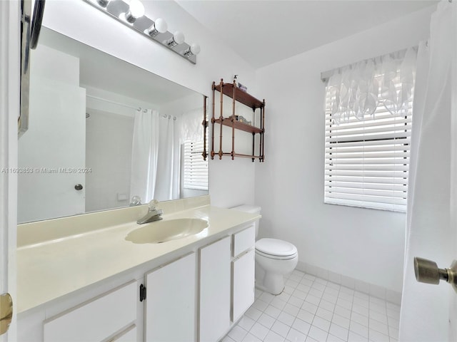 bathroom featuring tile patterned flooring, vanity, a healthy amount of sunlight, and toilet