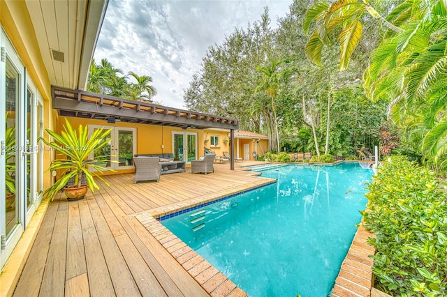 view of pool with french doors, ceiling fan, and a wooden deck