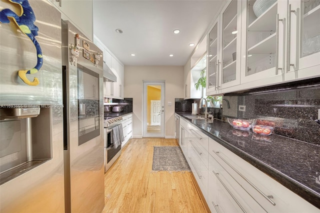 kitchen featuring white cabinets, light wood-type flooring, stainless steel appliances, and tasteful backsplash